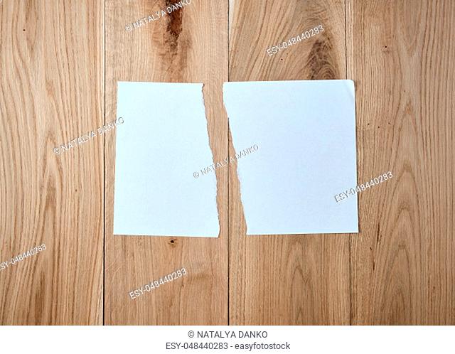 half torn blank white sheet on a wooden background, close up