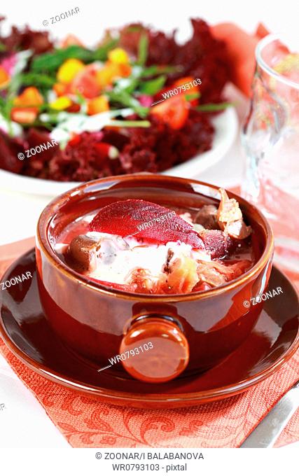 Red cabbage soup with beetroot borscht - Russian national dish with vegetable salad in background