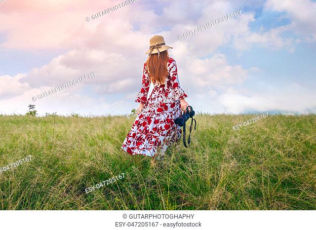 Woman standing on meadow and holding camera. Travel concept. Vintage tone