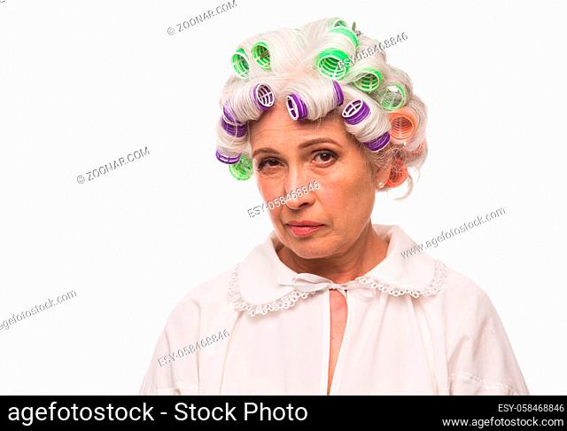 Portrait of serious grandmother with rollers on in studio. Beautiful senior lady posing for photographer