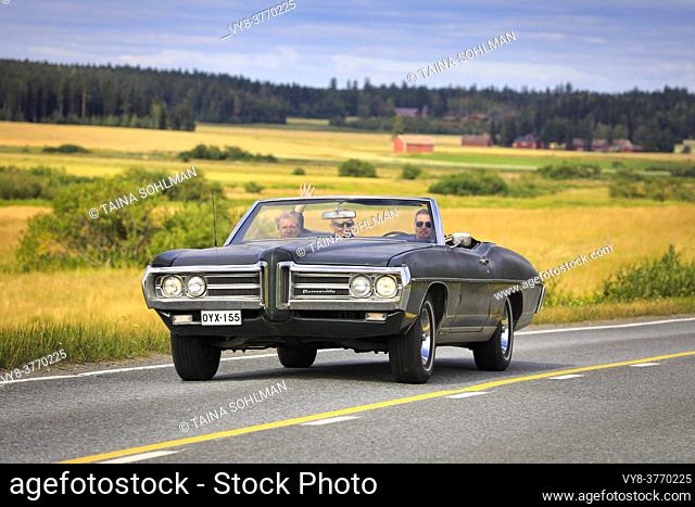 Three men enjoying a drive on black Pontiac Bonneville classic car on Maisemaruise 2019 car cruise. Vaulammi, Finland. August 3, 2019
