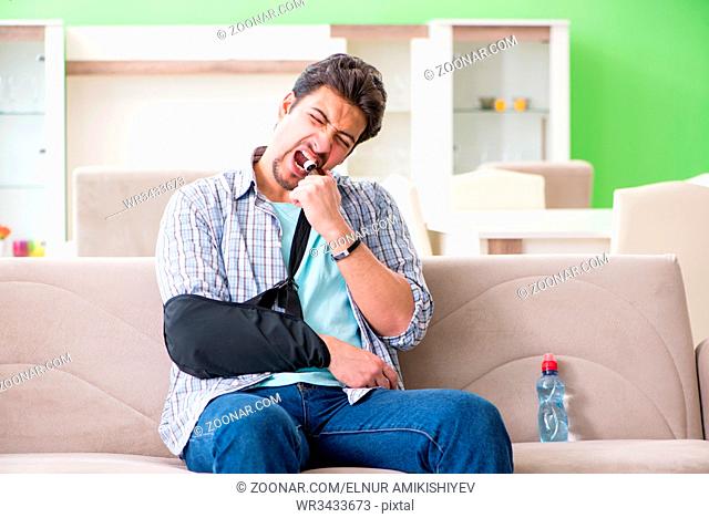 Young student man with hand injury sitting on the sofa