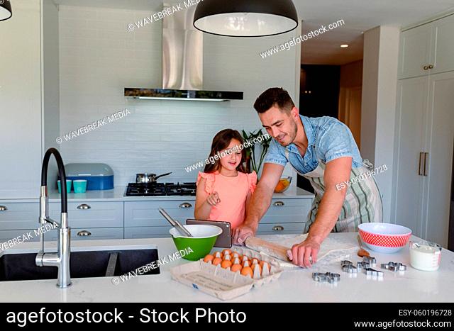 Happy caucasian father and daughter baking together, making cookies in kitchen