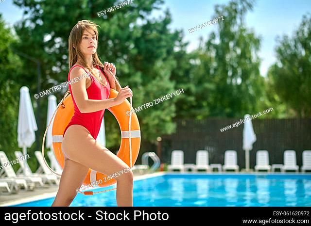 Lovely sporty young woman dressed in the swimsuit carrying the swim tube over her shoulder