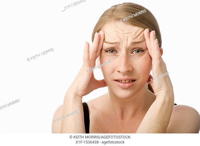 a young caucasian woman with a headache rubbing her forehead to relieve the pain, UK
