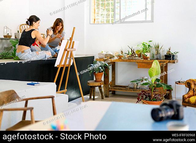 Female painters sitting on retaining wall while painting in studio