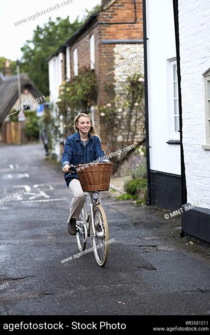Young blond woman cycling down a village street