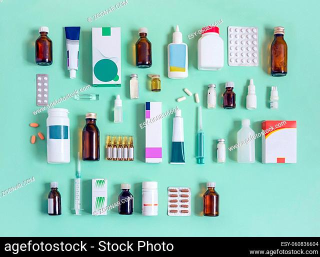 Various forms of drugs: tablets, ampoules, tinctures, blister packaging on a light green background. Place to insert text, top view