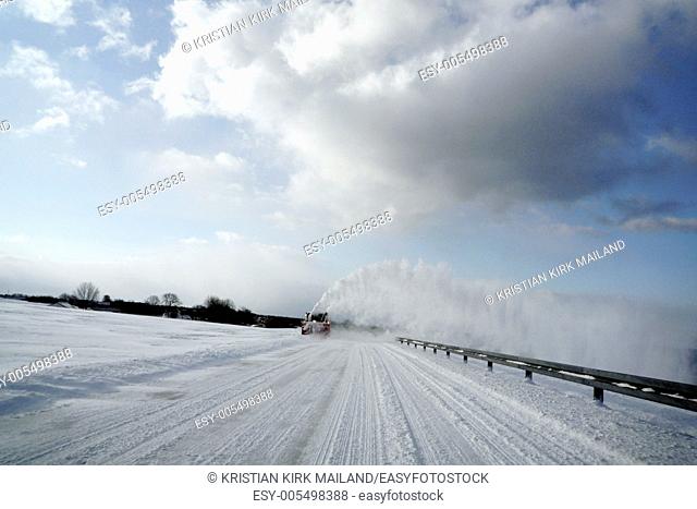 Snowblower clears the road. Clouds and snow. Denmark