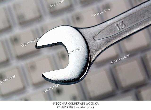 Ein Schraubenschlüssel als Werkzeug auf einer Computer Tastatur. Symbolfoto für Datenschutz, online Kriminalität, und Sicherheit im Internet