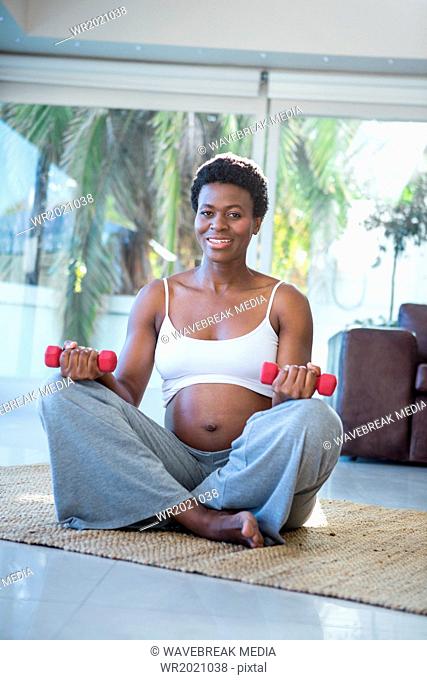 Portrait of happy woman with dumbbells sitting