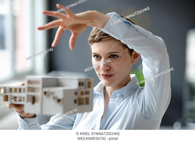 Confident businesswoman holding architectural model in office