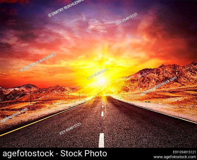 Travel forward concept background - vintage retro effect filtered hipster style image of road in Himalayas with mountains and dramatic clouds on sunset