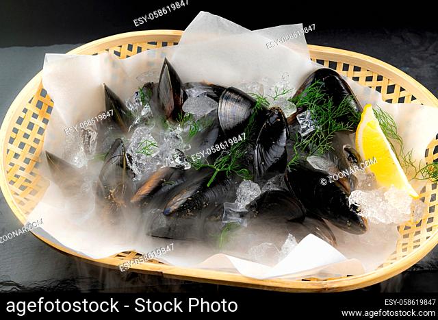 Fresh black mussel seafoon in basket with lemon. Fresh food and market concept