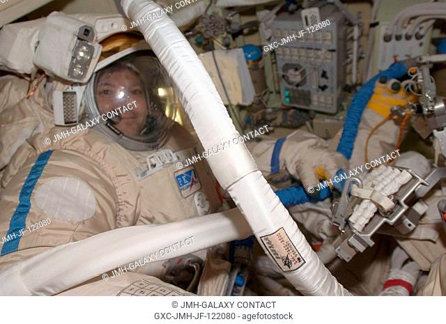 Attired in their Russian Orlan spacesuits, Russian Federal Space Agency cosmonauts Sergei Volkov (right, partially out of frame) and Oleg Kononenko