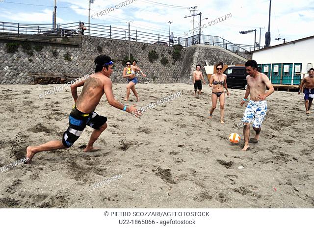 Kamakura, Kanagawa, Japan, friends playing beach soccer at Yuigahama Beach in summer