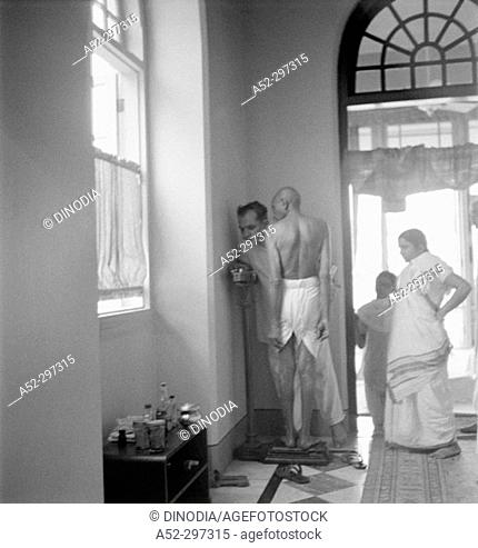 Gandhi standing on weighing scales at Birla House. Mumbai. Maharashtra. India. 1945