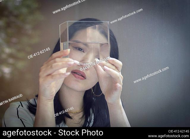 Curious female designer looking at cube with water