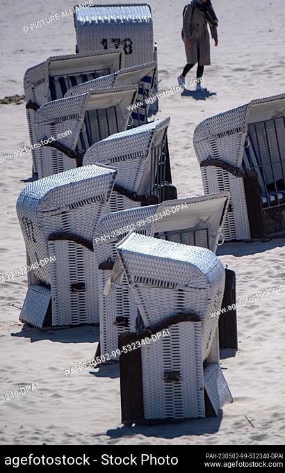 02 May 2023, Mecklenburg-Western Pomerania, Heringsdorf: Shuttered beach chairs stand on the beach of the Baltic resort of Heringsdorf on the Baltic island of...