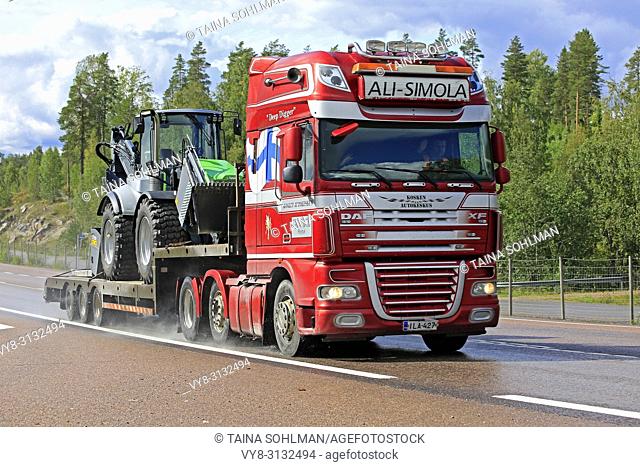 Orivesi, Finland - August 27, 2018: DAF XF truck of Ali-Simola transports agricultural tractor on gooseneck trailer along wet highway on a rainy day