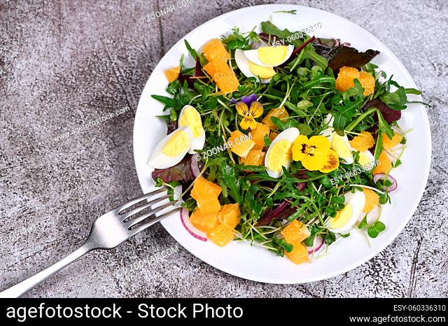 Spring fruit, citrus and vegetable salad from a mix of lettuce leaves and sprouts of radish and lentils, arugula, microgreens, quail egg wedges