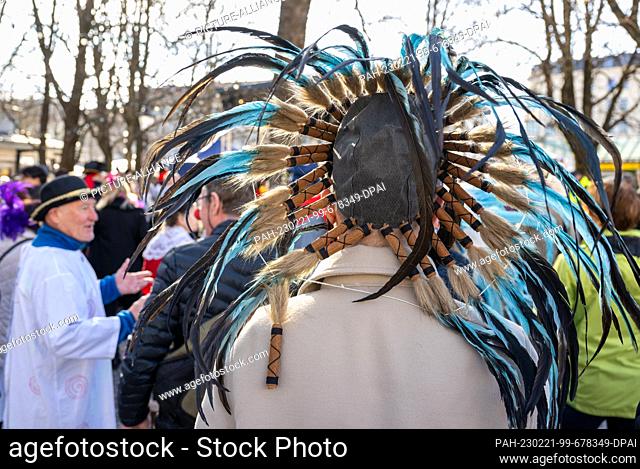 21 February 2023, Bavaria, Munich: A man with feathers on his head stands at the dance of the market women at the Viktualienmarkt on Shrove Tuesday
