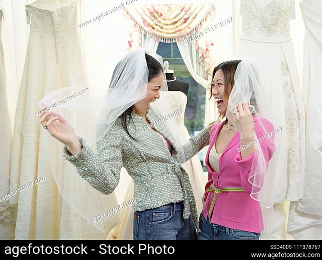 Young women wearing veils in a bridal boutique