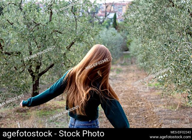 Redhead woman running amidst trees at farm