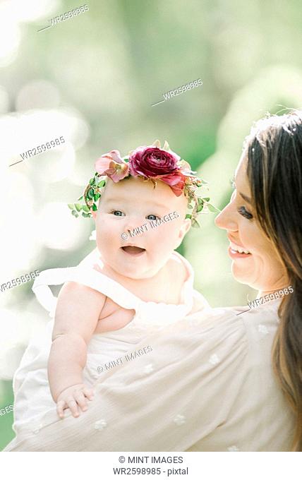 Portrait of a smiling mother and baby girl with a flower wreath on her head