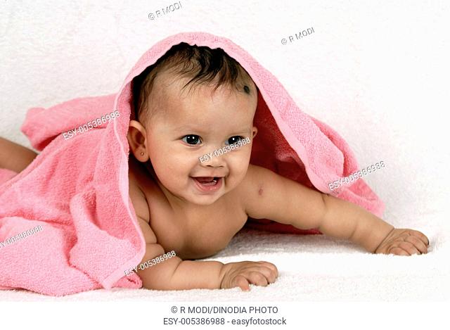 Five month old baby girl lying on white towel covered with pink towel MR736P