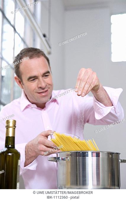 Man spicing spaghetti with salt