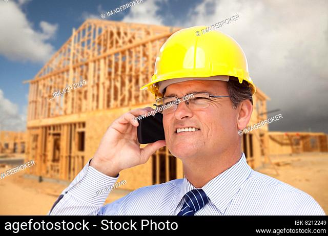 Contractor in hardhat at construction site talks on his cell phone