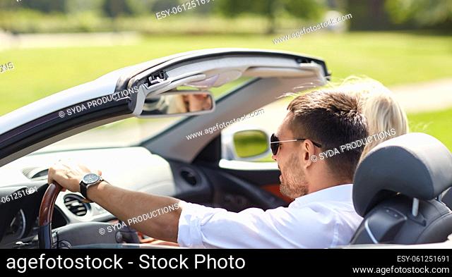 happy couple driving in convertible car