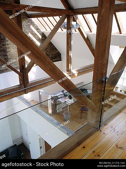 View from loft extension exposed wooden ceiling beams polished floorboards glass balustrade Interiors rooms open-plan open plan split level split-level modern...