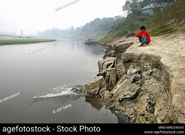 Kamrul, 11, sat beside an eroding river bank on Brahmaputra River in Manikganj, Bangladesh in tearful eyes as erosion continues to take place putting his family...