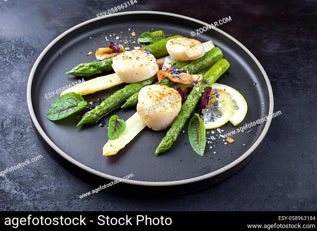 Traditional barbecue scallops with green and white asparagus offered as close-up on a modern design plate