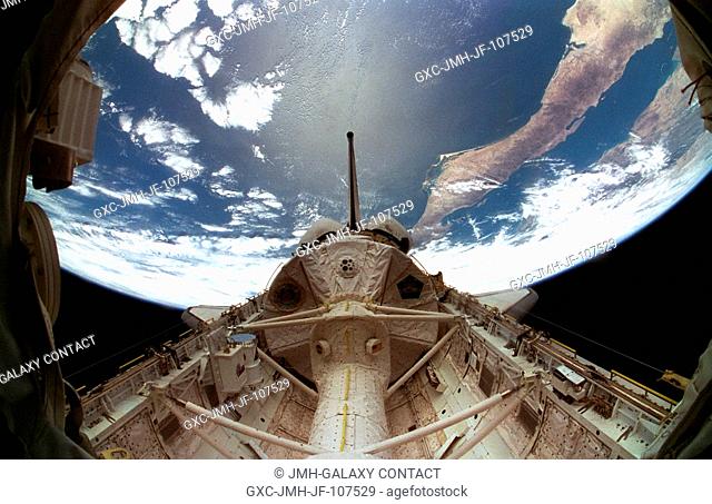 A special lens on a 35mm camera gives a fish-eye effect this view of the Spacelab Module backdropped over the Pacific Ocean