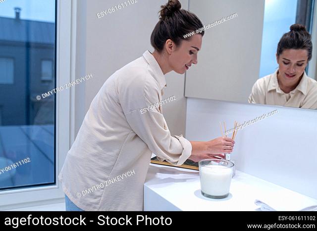 Air freshener. A young woman putting air freshener in the bathroom
