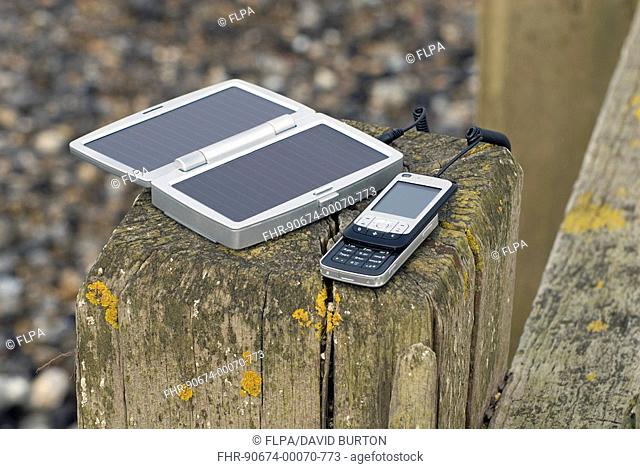 Mobile cellular phone, attached to solar powered battery charger, England