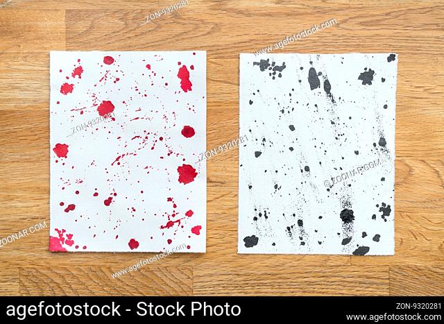 Two piece of papers spotted with ink in a wooden background