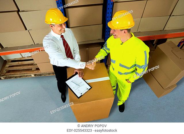Smiling Warehouse Manager And Worker Shaking Hands In Warehouse