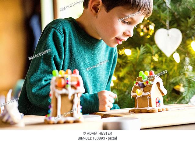 Mixed race boy building gingerbread house