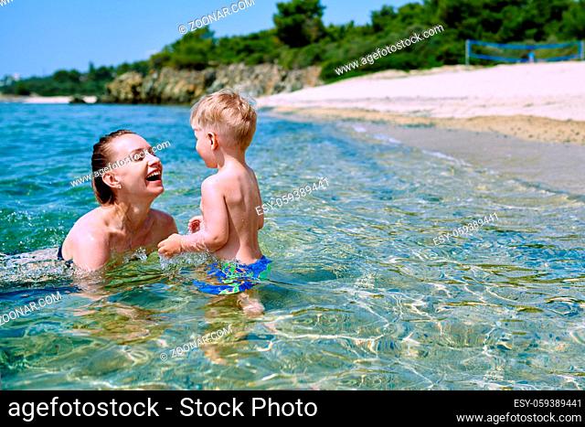 Two year old toddler boy on beach with mother