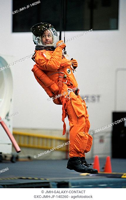 Astronaut Stephen K. Robinson, STS-114 mission specialist, simulates a parachute drop into water during an emergency bailout training session at the Neutral...