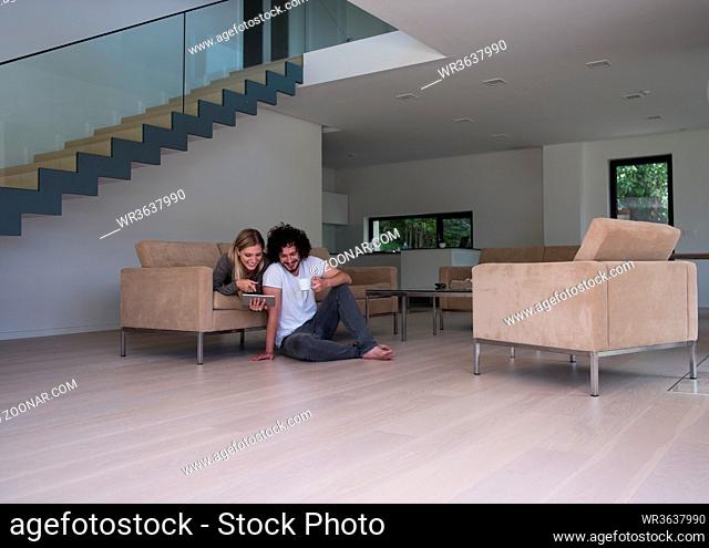 Young couple relaxing at luxurious home with tablet computers reading in the living room on the sofa couch