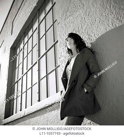 Young woman, leaning on building