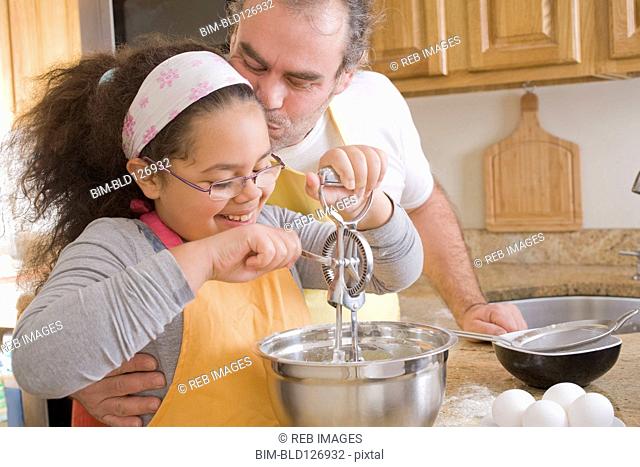 Hispanic father and daughter baking in kitchen