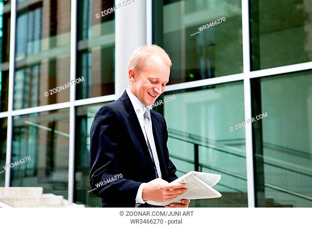 junger erfolgreicher Geschäftsmann ließt Zeitung im freien auf einer treppe