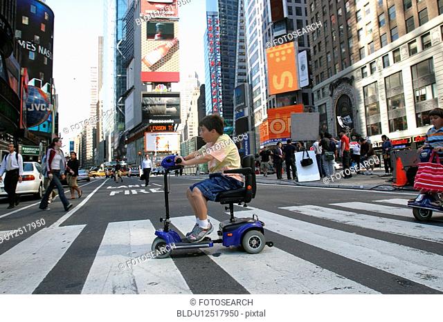 Boy using scooter to cross a street in New York City