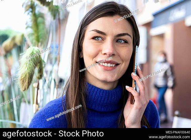 Smiling beautiful woman talking on mobile phone while looking away